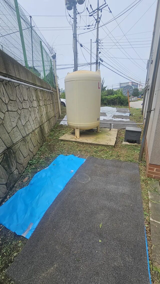 주택잡초제거 작업 중 외벽과 기초 경계를 따라 잡초를 정리하는 모습